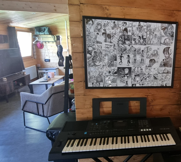 Toile L'Attaque des Titans accrochée sur un mur en bois, au-dessus d'un clavier